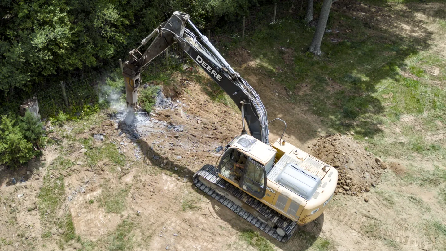 Hydraulic Rock breaker attached to a full size excavator helping complete site work, excavation, and grading projects in Winchester, VA.