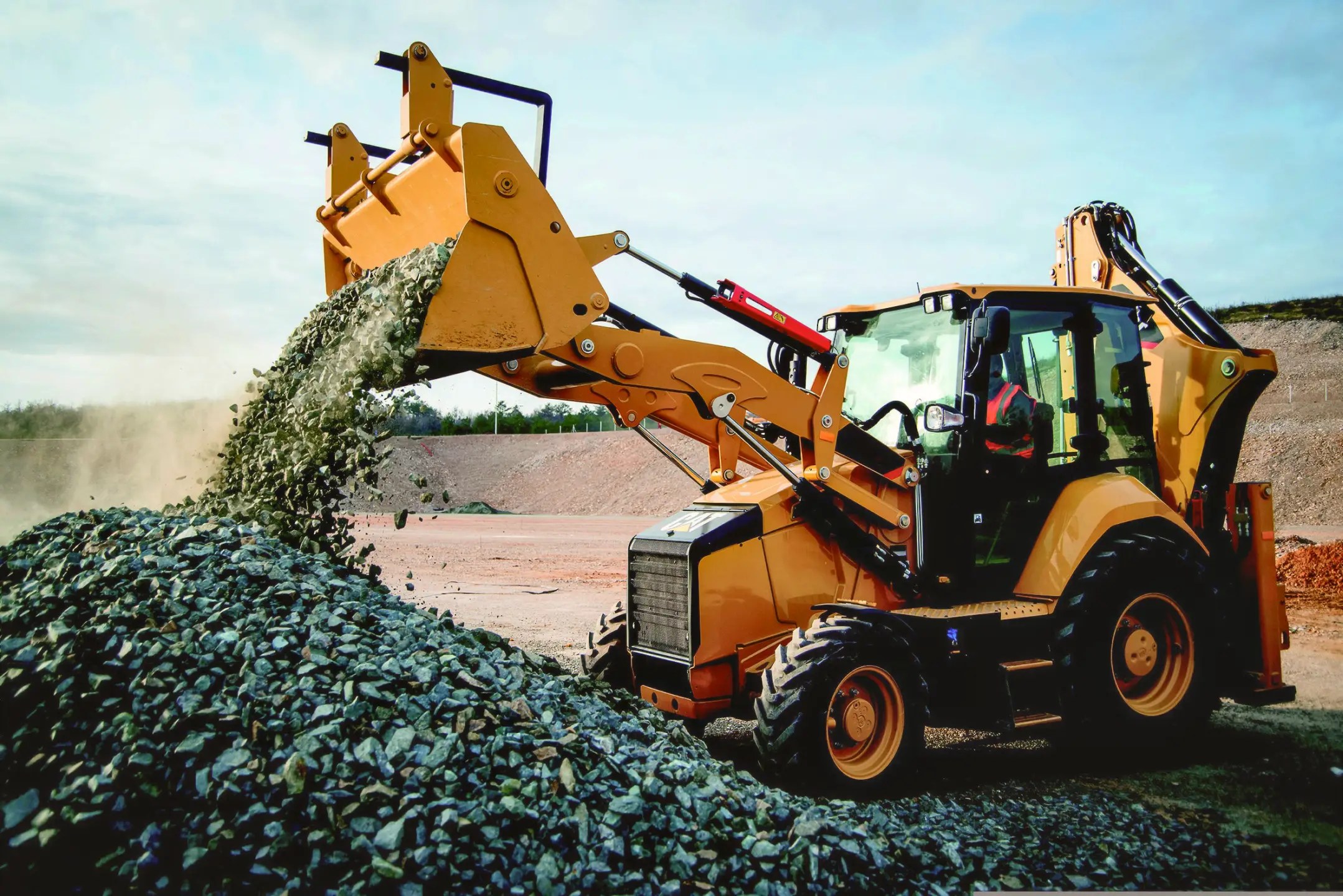 Backhoe loader moving stone and gravel for a subgrade job.